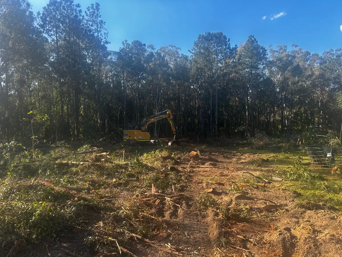 Excavator clearing timber and debris on a rural property in Queensland
