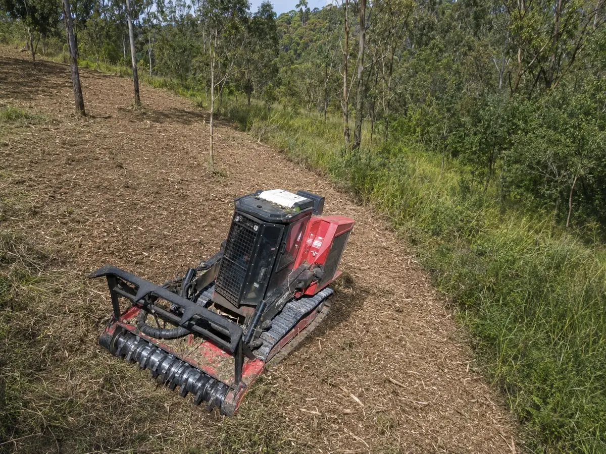 Forestry mulcher creating a firebreak through tall grass on a rural property in Queensland