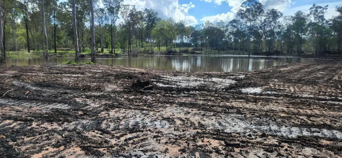Muddy farm dam site with machinery tracks showing seepage and silt issues in Queensland
