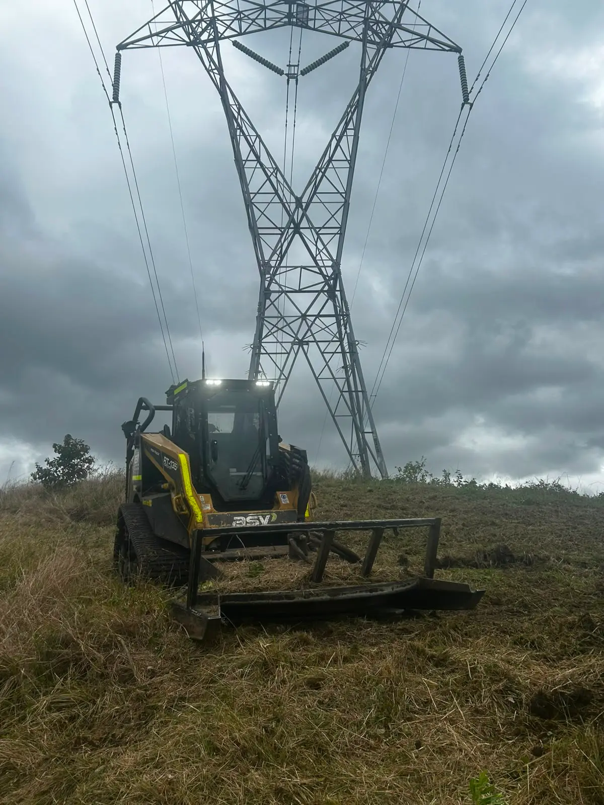 Mulching machine clearing vegetation beneath a high voltage transmission tower in Queensland